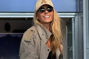 Adriane Galisteu posa no aeroporto de óculos escuros e boné