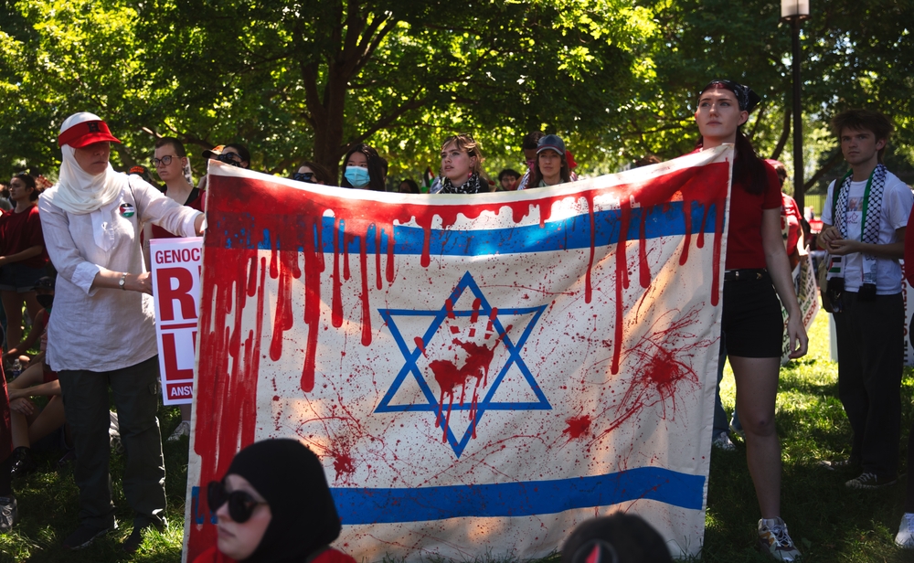Protestantes seguram uma bandeira de Israel ensanguentada em Washington, Estados Unidos, em junho de 2024 | Foto: Johnny Silvercloud/Shutterstock